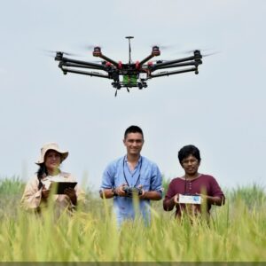 A vibrant group of friends relaxes on the grass while a drone hovers playfully above them, capturing the energy and excitement of flying together. The warm sunlight and open space highlight the joy of shared experiences, making this scene perfect for promoting family memberships, group sessions, and community flying at Hope Farm Flight Club.